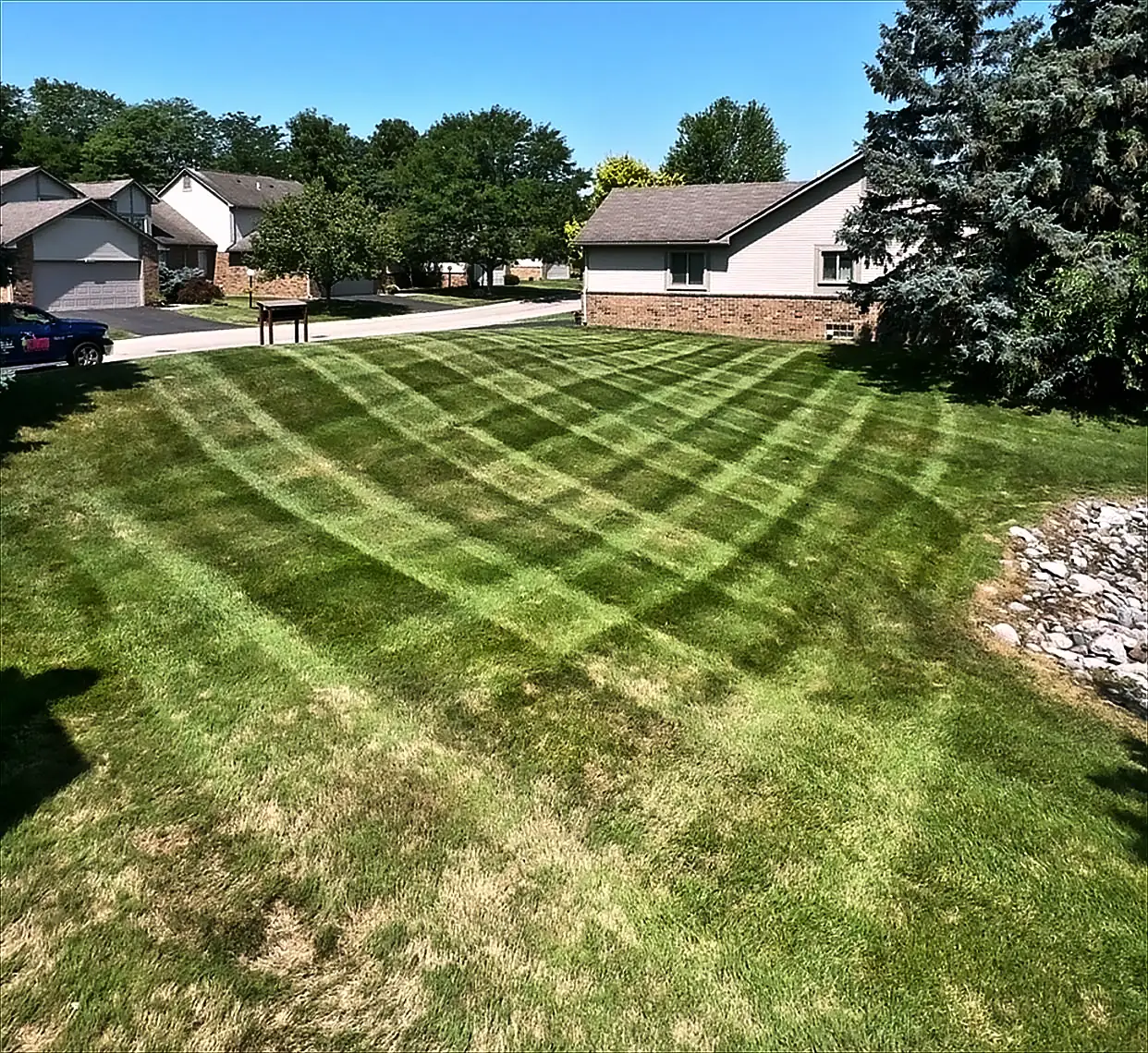 A freshly mown lawn with curved mowing stripes in front of ranch homes